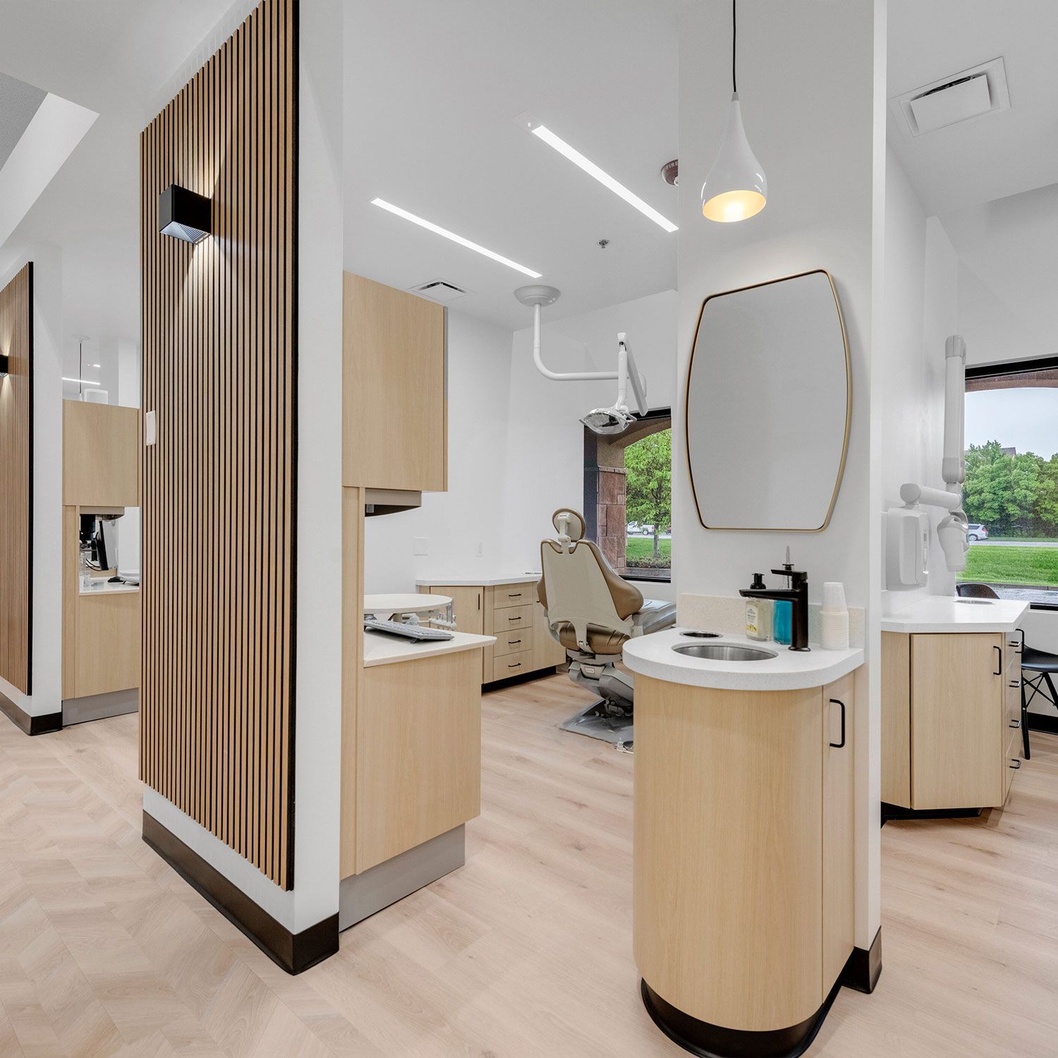 a dental office with wooden cabinets and a mirror on the wall .