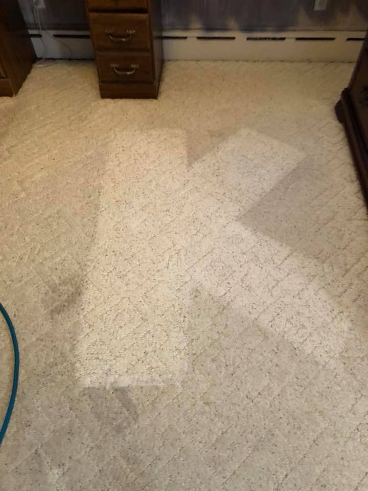 a dirty carpet in a room with a desk and dresser .