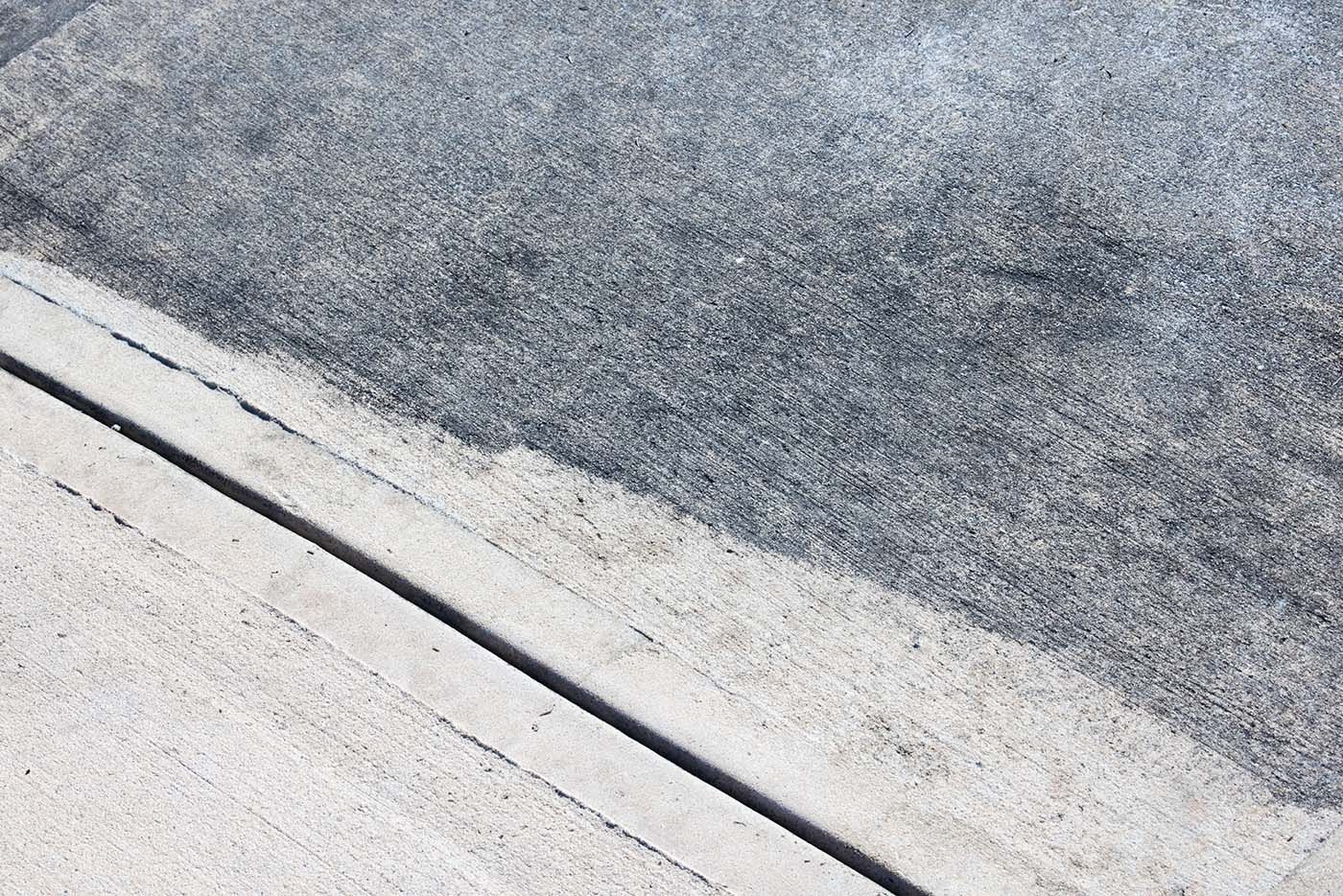 A concrete driveway with visible back staining in Suffolk County NY