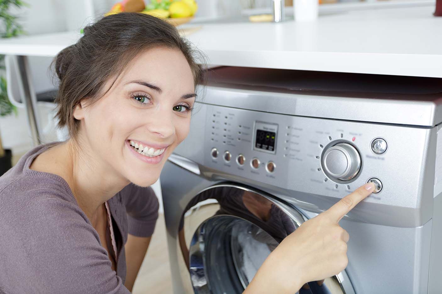a woman is pressing a button on a washing machine .