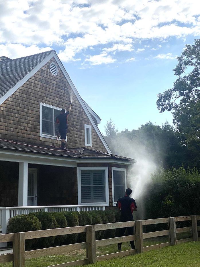 a man is spraying water on the roof of a house .