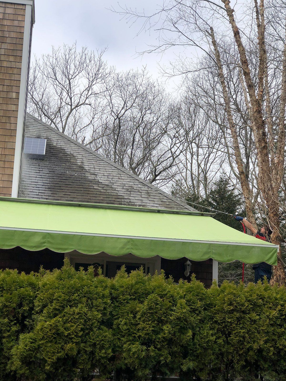 a green awning is being installed on the side of a house .