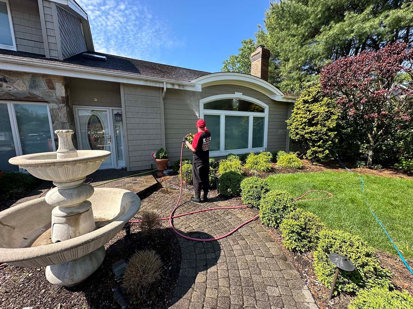 K.O.S. Cleaning technician soft washing a home in Suffolk County, New York