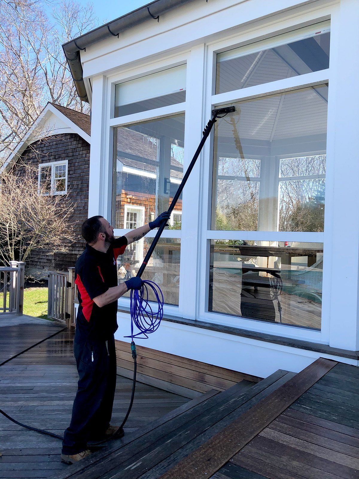 a man is cleaning a window with a high pressure washer .