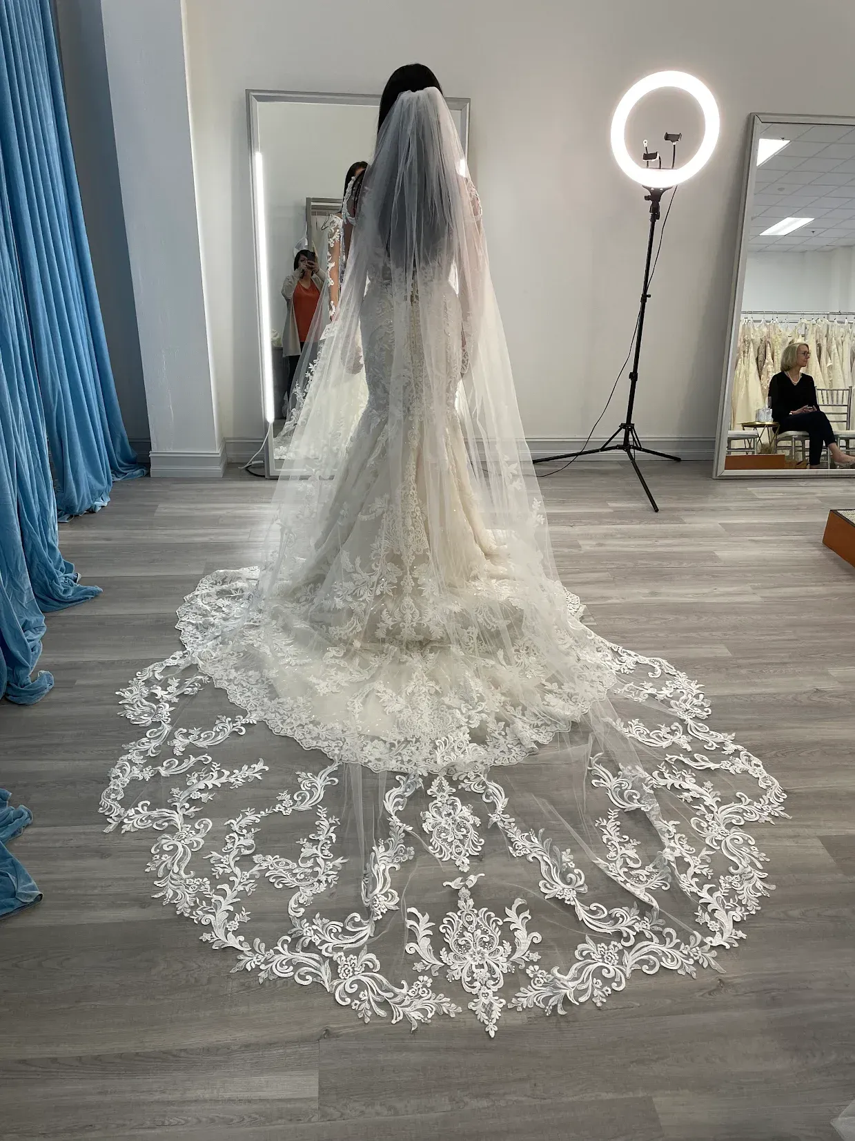 Wedding dress with long, lace-trimmed train and veil in a bridal shop.