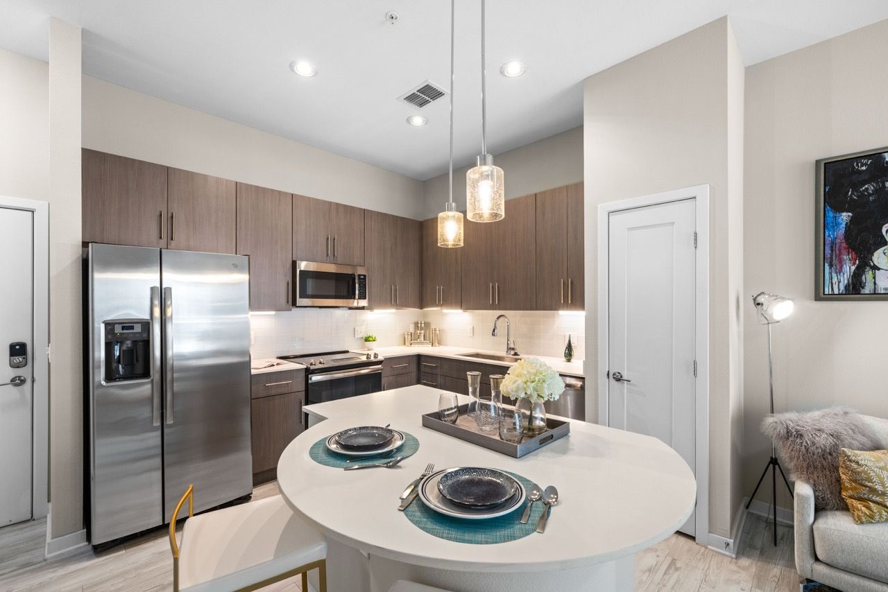 Modern kitchen with stainless steel refrigerator, appliances, and a round white island.