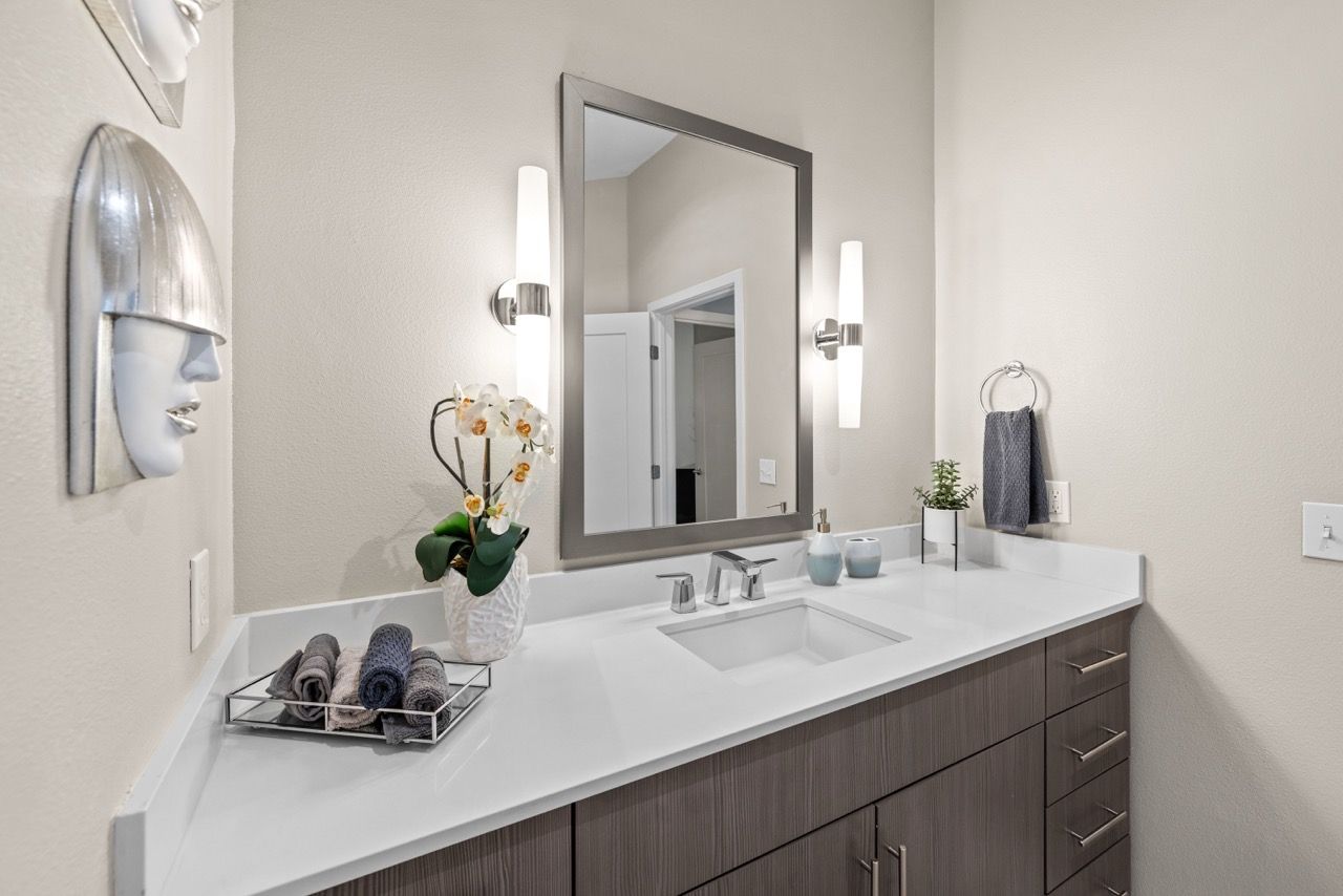Bathroom vanity with single sink, large framed mirror, and wall-mounted lights.
