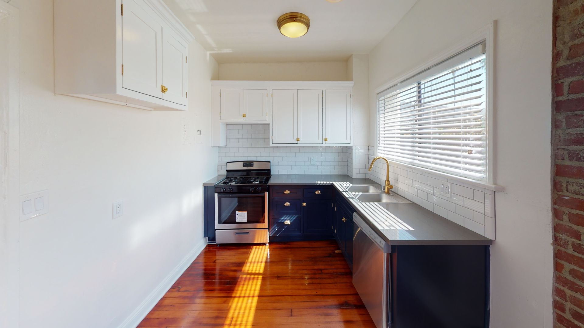 Small kitchen with blue and white cabinets, stainless steel appliances, and wood floors.