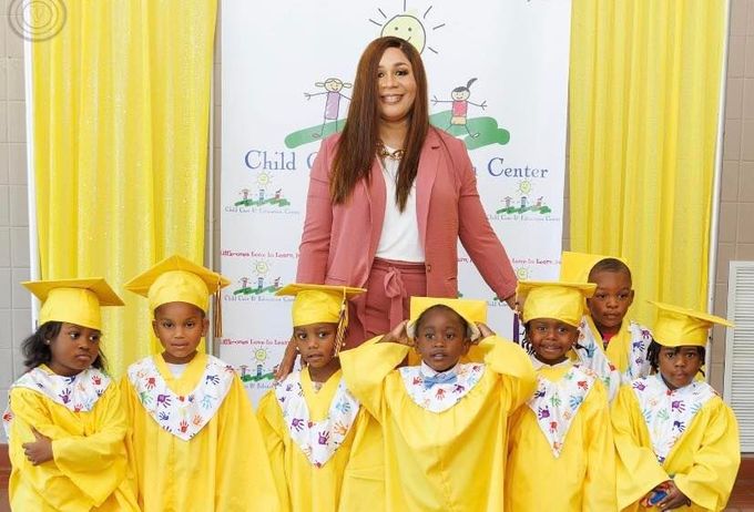 A woman is standing next to a group of children wearing graduation caps and gowns.