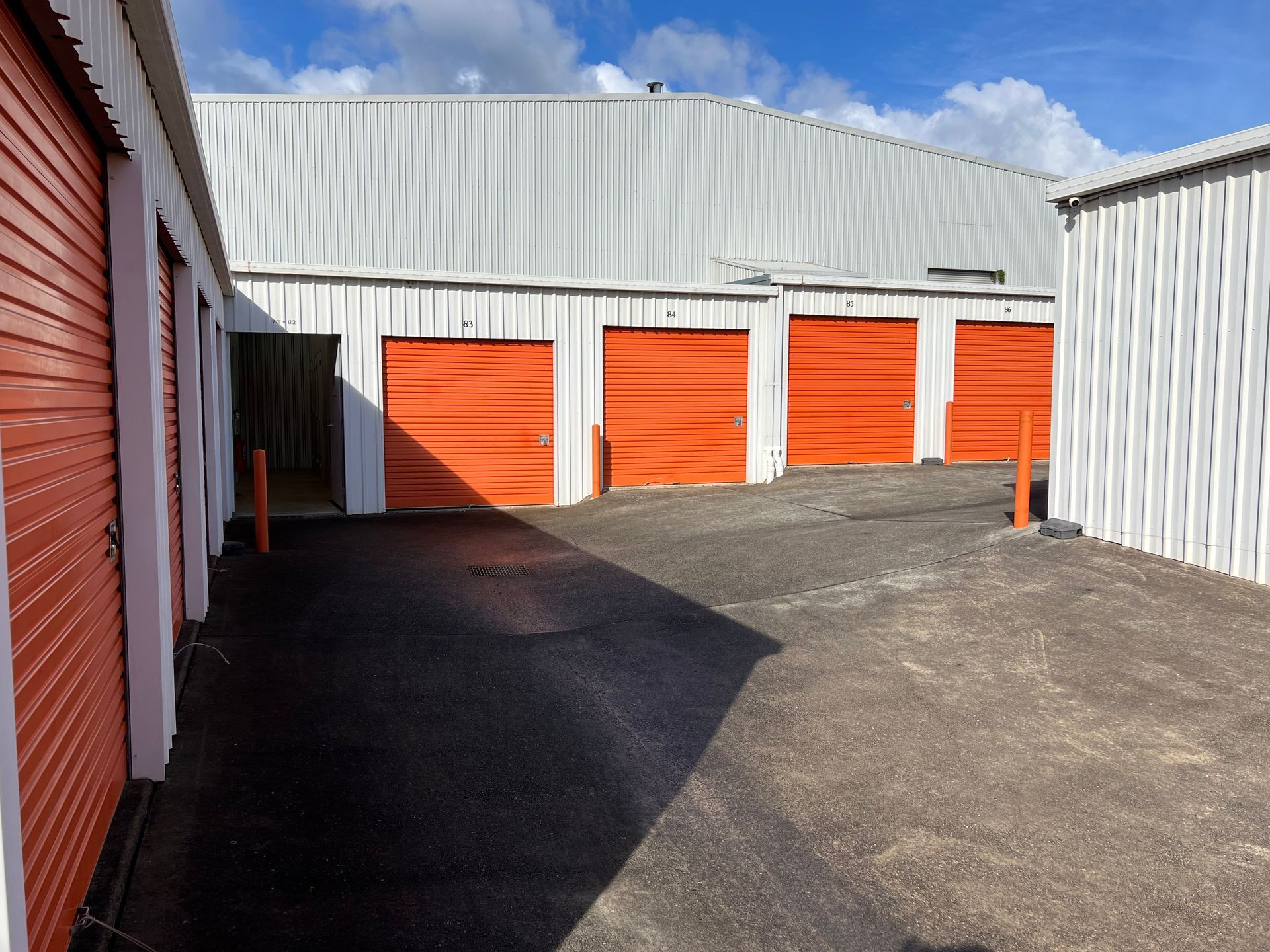 A Row Of Storage Units With Red Doors On A Cloudy Day  — Acacia Mini Storage in Port Macquarie, NSW