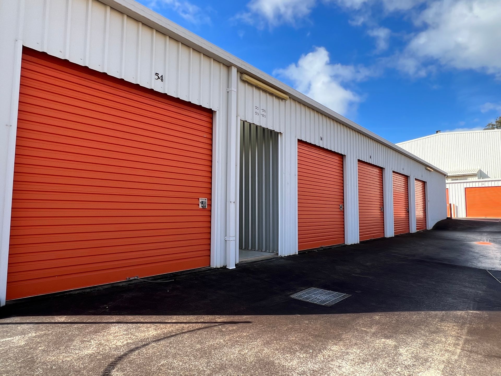 A long hallway with orange doors and a red fire extinguisher.  — Acacia Mini Storage in Port Macquarie, NSW