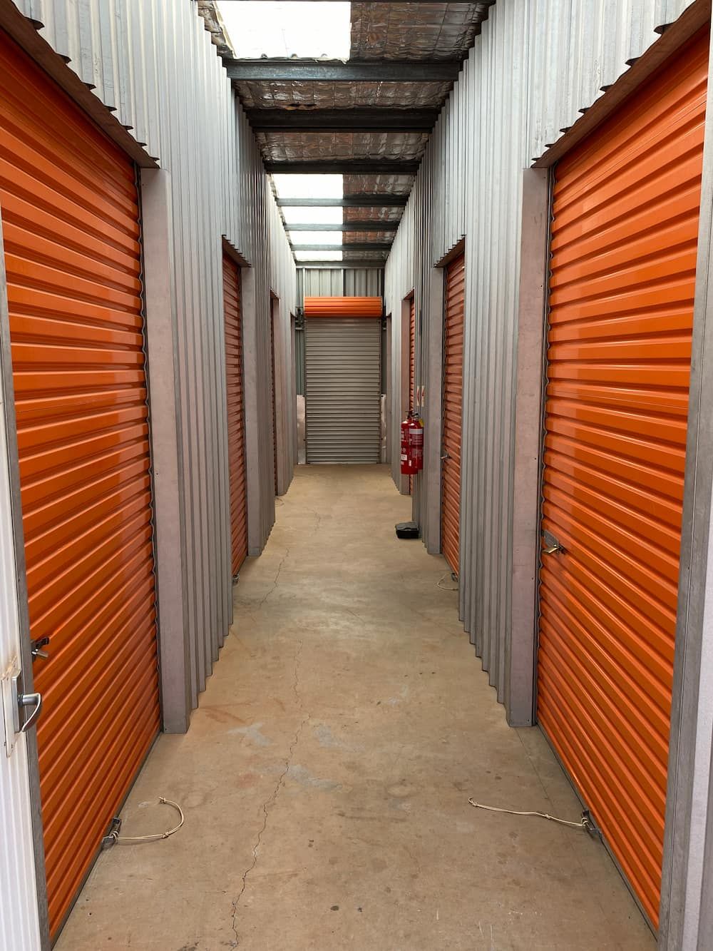 A Long Hallway With Orange Shutters On The Doors  — Acacia Mini Storage in Port Macquarie, NSW