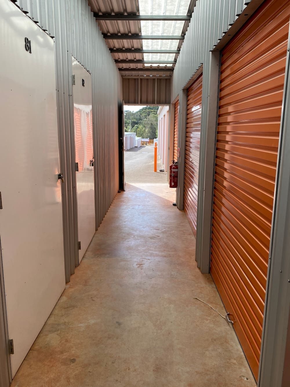 A Long Hallway With Orange Shutters On The Doors  — Acacia Mini Storage in Port Macquarie, NSW