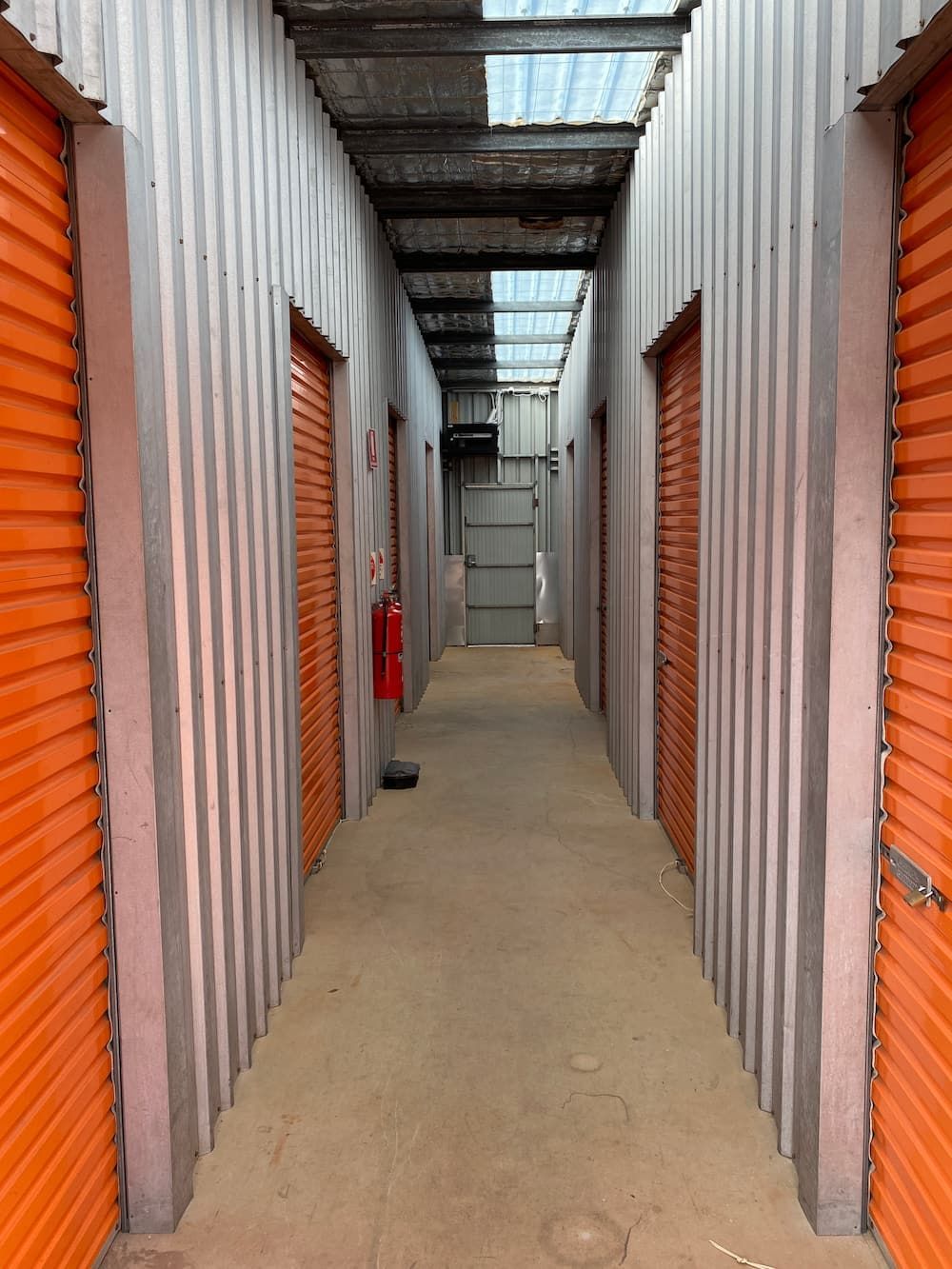 A Long Hallway With Orange Doors And A Red Fire Extinguisher  — Acacia Mini Storage in Port Macquarie, NSW