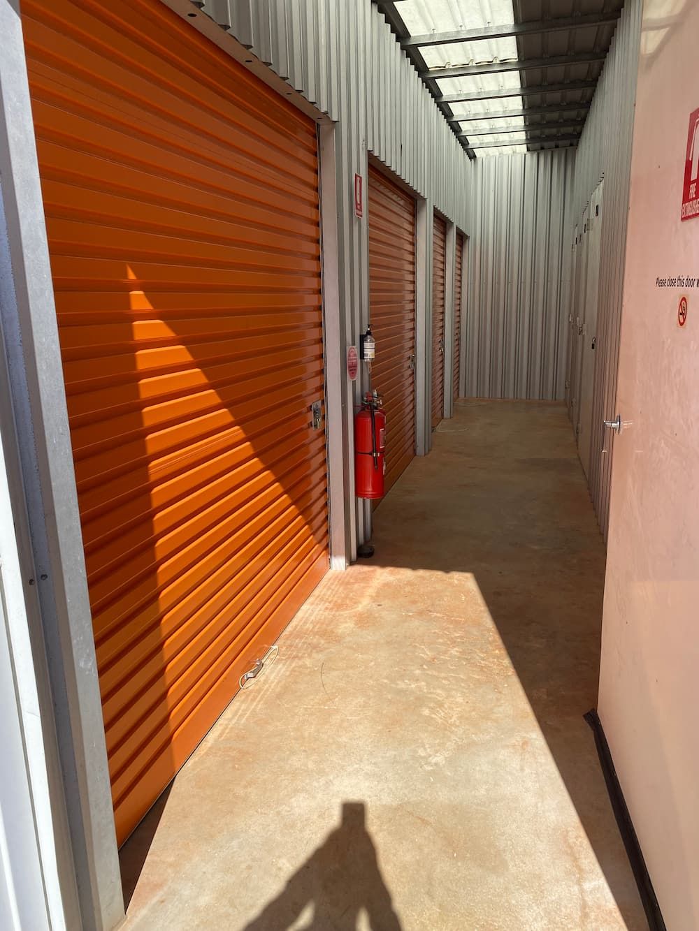 A Long Hallway With Orange Doors And A Red Fire Extinguisher  — Acacia Mini Storage in Port Macquarie, NSW