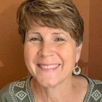 a woman with short hair and earrings is smiling for the camera .