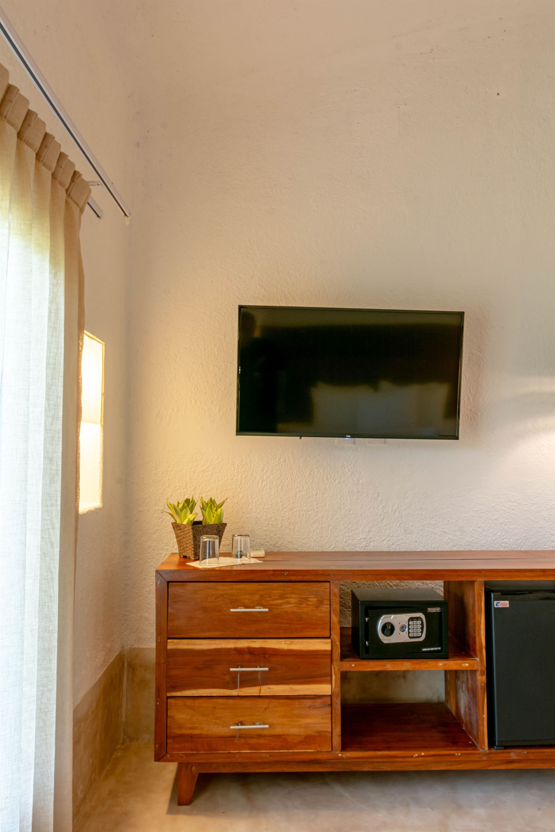 Una habitación con una cómoda y un televisor de pantalla plana en la pared