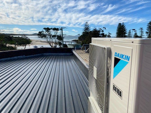 A daikin air conditioner is sitting on top of a metal roof-Refrigeration & Air Conditioning in Kempsey, NSW