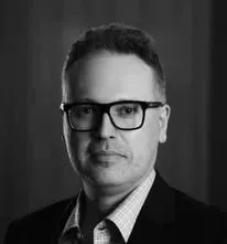 Uma foto em preto e branco de um homem usando óculos e terno.