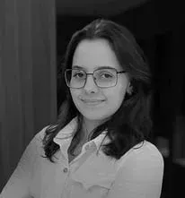 Uma foto em preto e branco de uma mulher usando óculos e uma camisa branca.