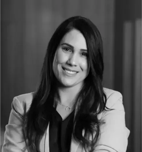 Um homem usando óculos e uma camisa branca está sorrindo em uma foto em preto e branco.