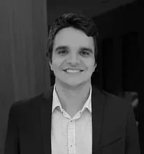 Um homem de terno e camisa branca está sorrindo em uma foto em preto e branco.