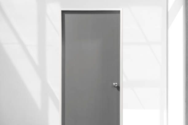 A Gray Door Is Sitting In A White Room Next To A Window — Laredo, TX — South Central Hardware Inc.