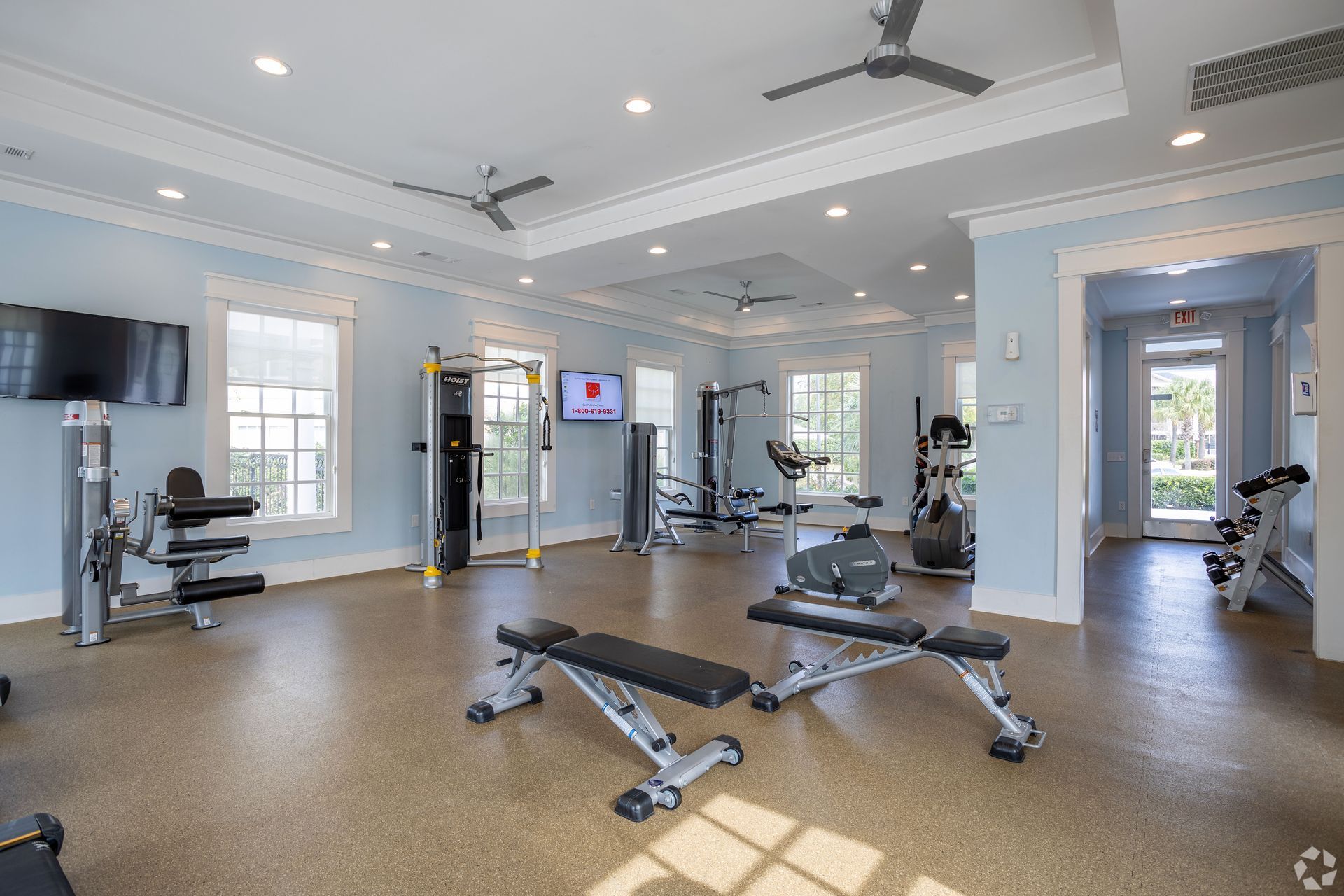 Gym interior with various exercise machines, light blue walls, and ceiling fans at Preserve at Godley Station in Pooler, GA.
