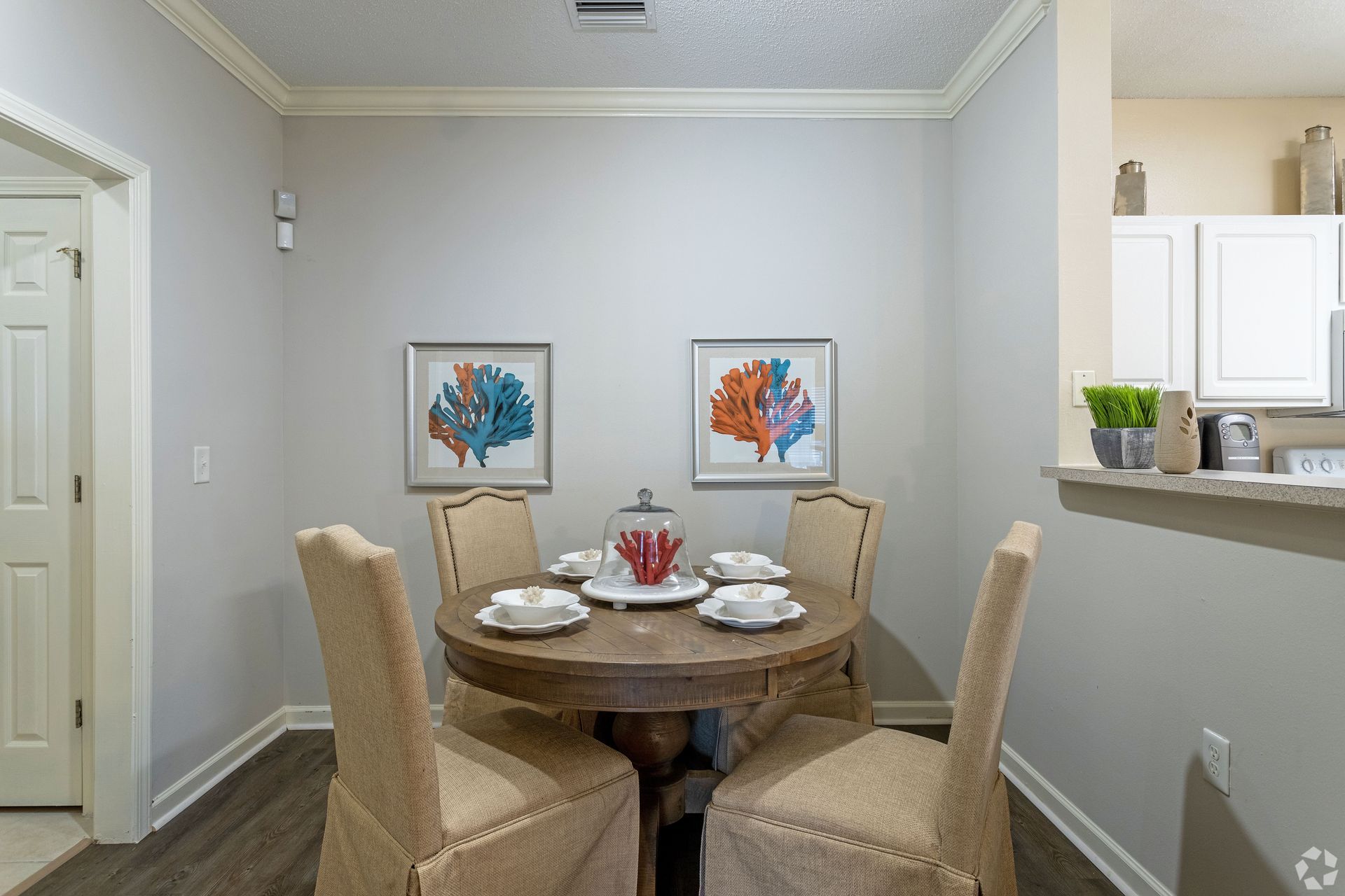 Dining room with a round wooden table, four chairs, artwork, and a white door at Preserve at Godley Station in Pooler, GA.