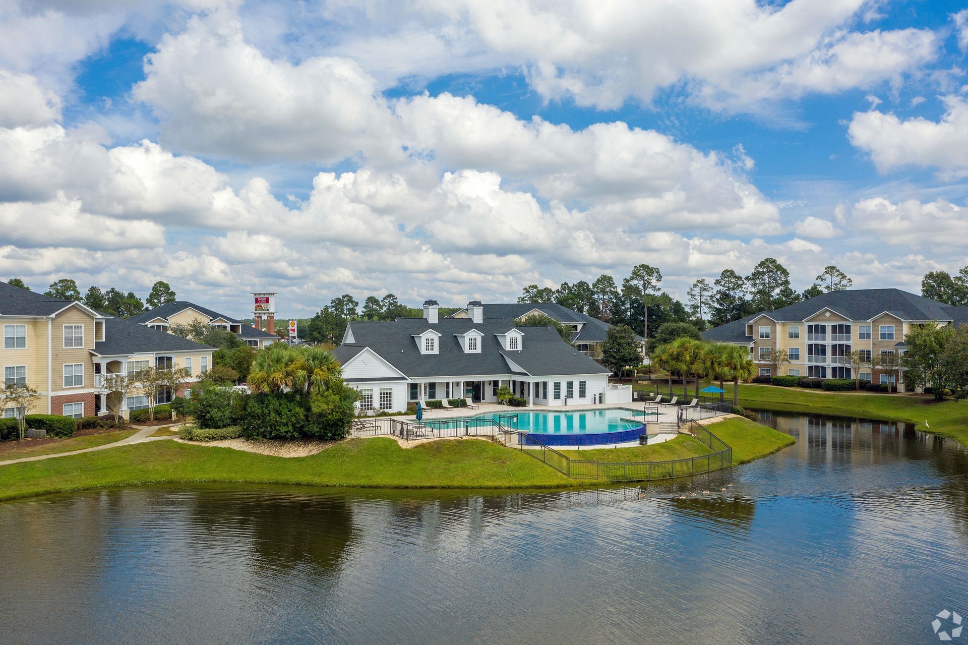 Apartment complex with a pool overlooking a lake on a sunny day at Preserve at Godley Station in Pooler, GA.