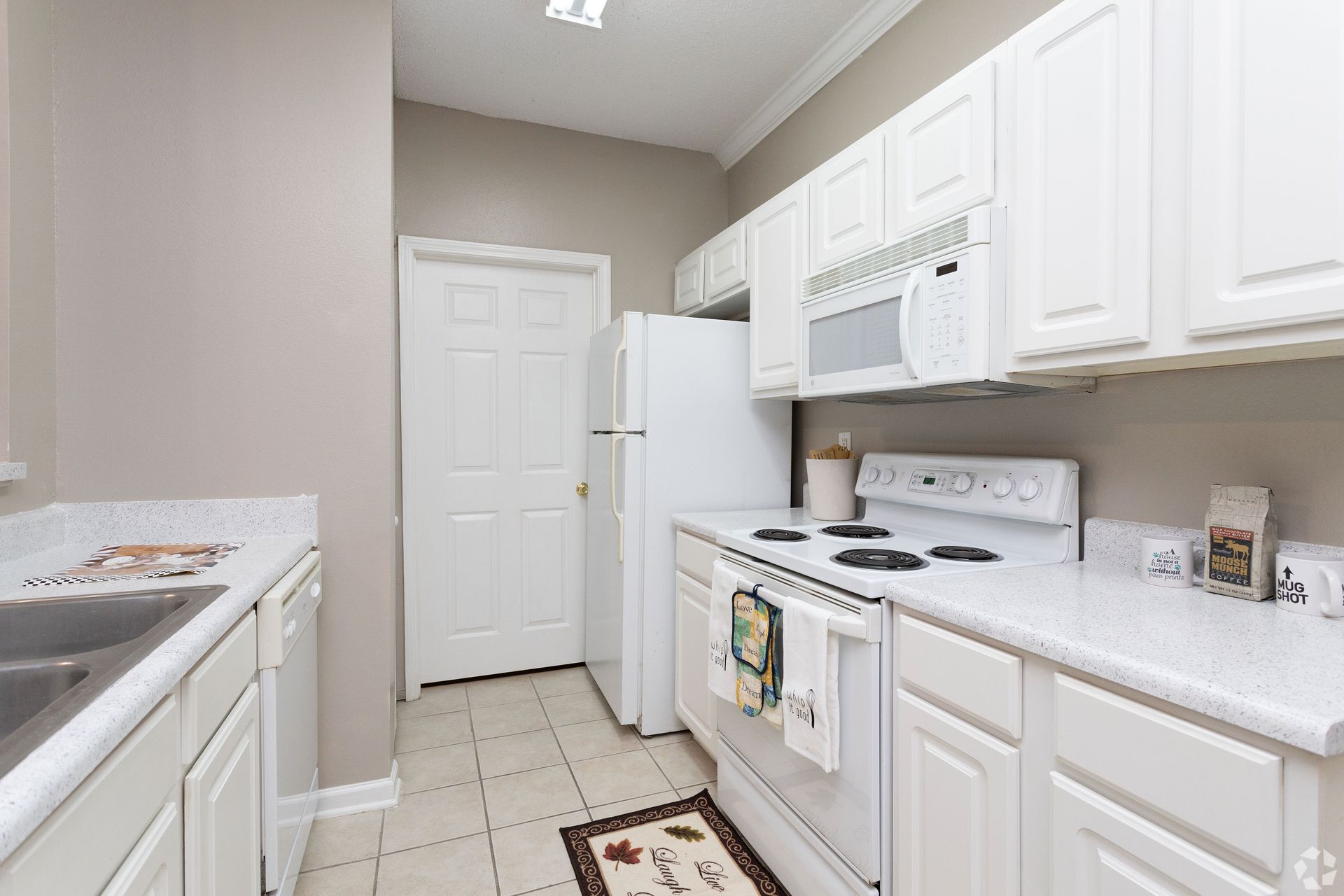 Bright kitchen with white cabinets, appliances, and countertops; breakfast bar at Preserve at Godley Station in Pooler, GA.