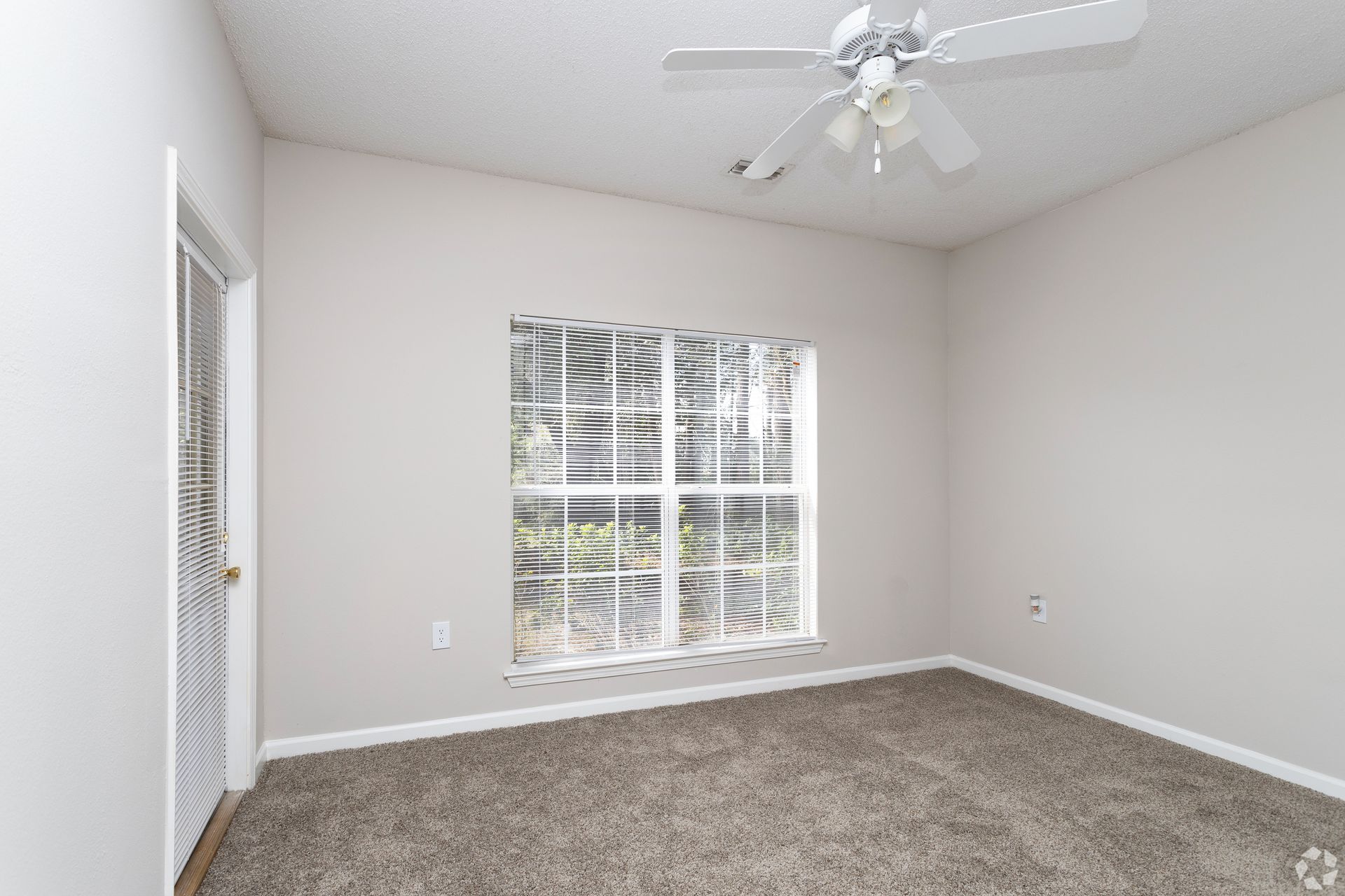 Empty room with carpet, a window with blinds, and a ceiling fan at Preserve at Godley Station in Pooler, GA.