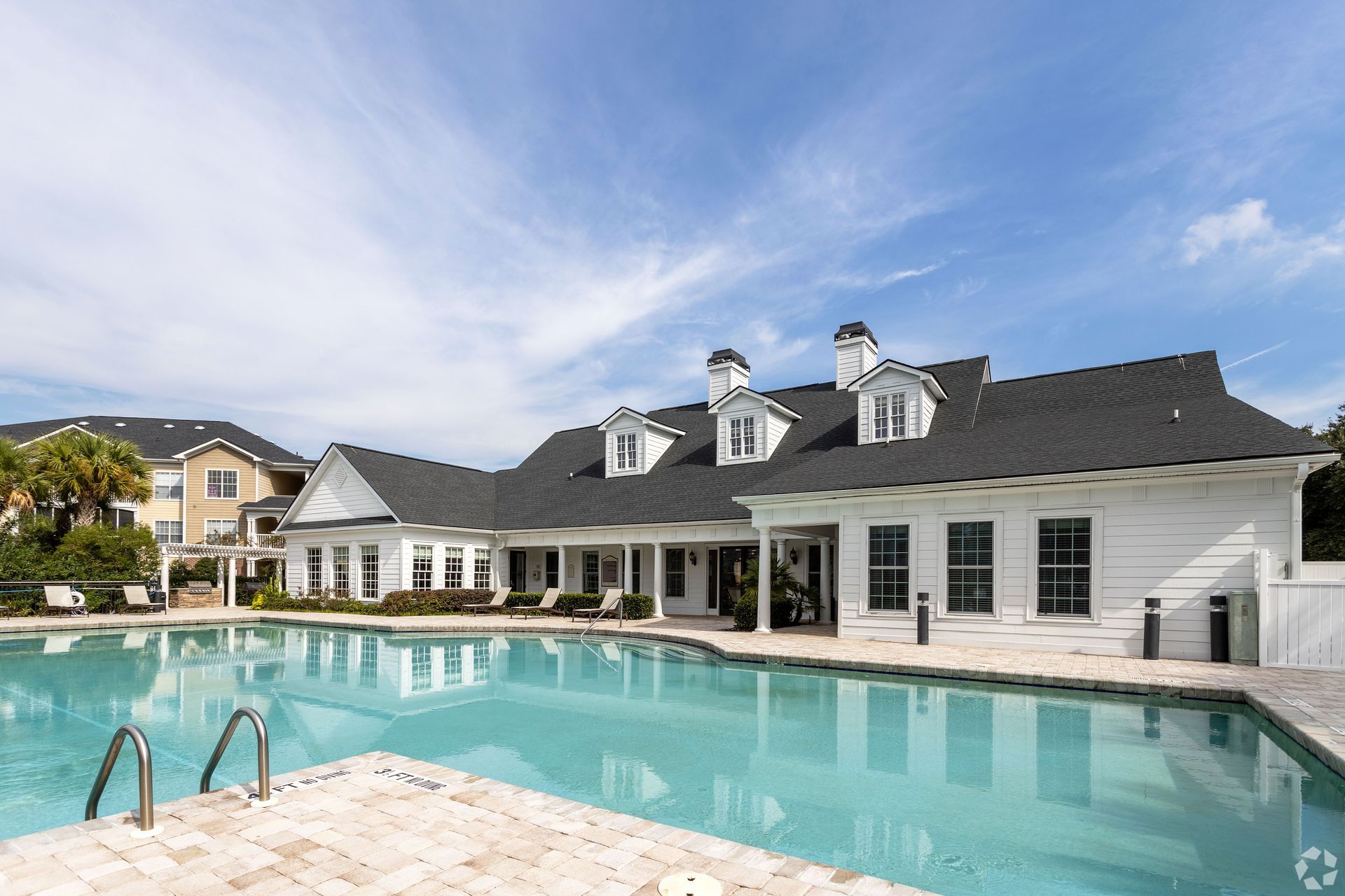 Swimming pool with white building, blue sky at Preserve at Godley Station in Pooler, GA.