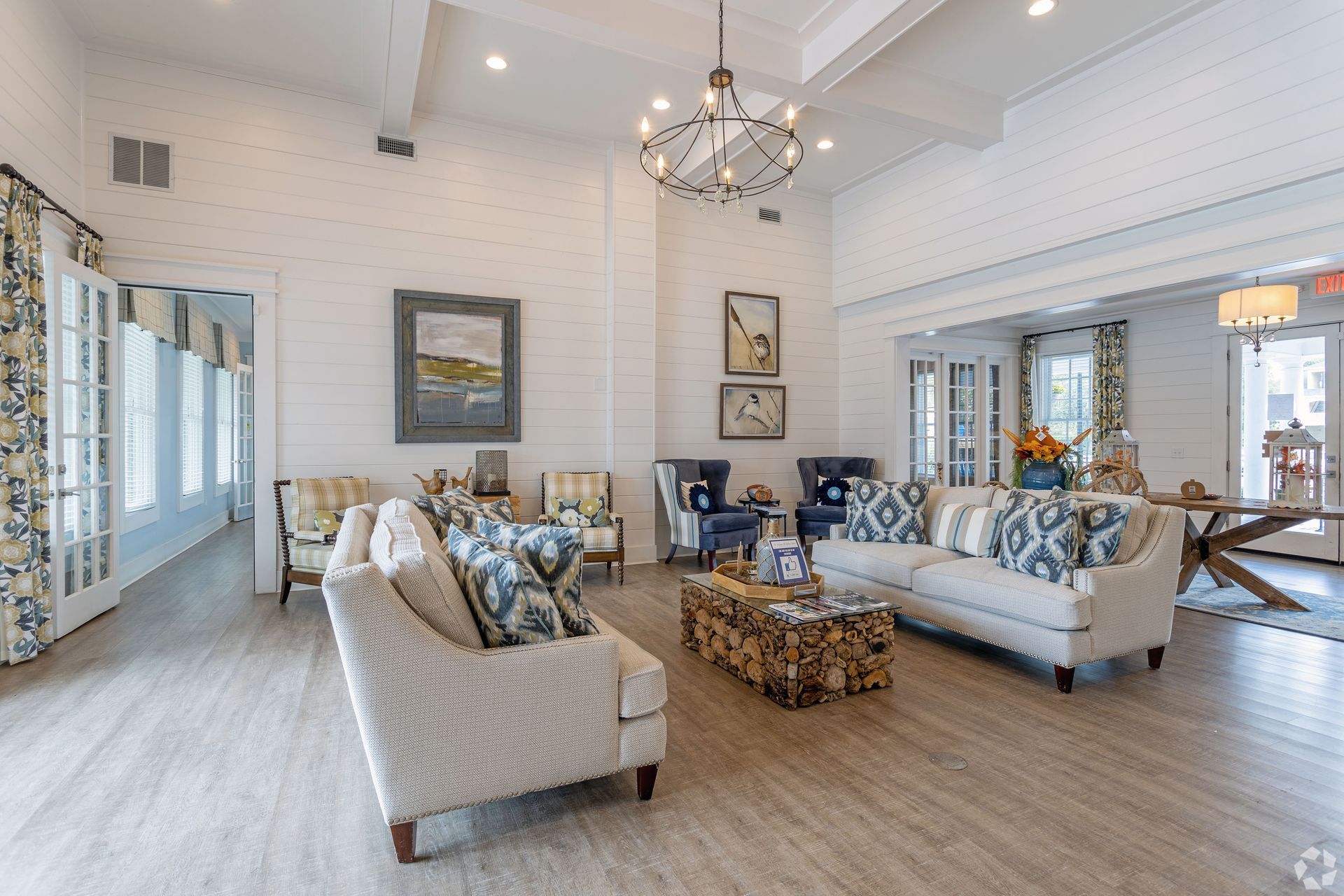 Spacious, bright living room with white walls, multiple sofas, armchairs, and a wood coffee table at Preserve at Godley Station in Pooler, GA.