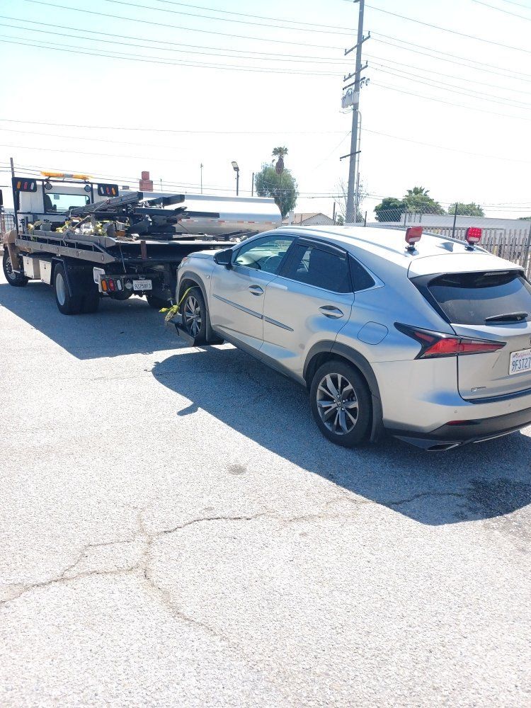 Silver SUV being towed by a tow truck on a sunny day.