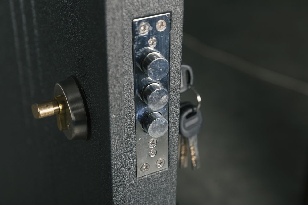 Primo piano di una porta grigio scuro con meccanismo di serratura argentato e chiavi.