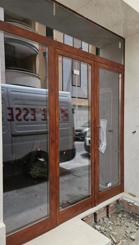 Porte in vetro con telaio in legno e finestra a falda. È visibile il riflesso del furgone con la scritta 