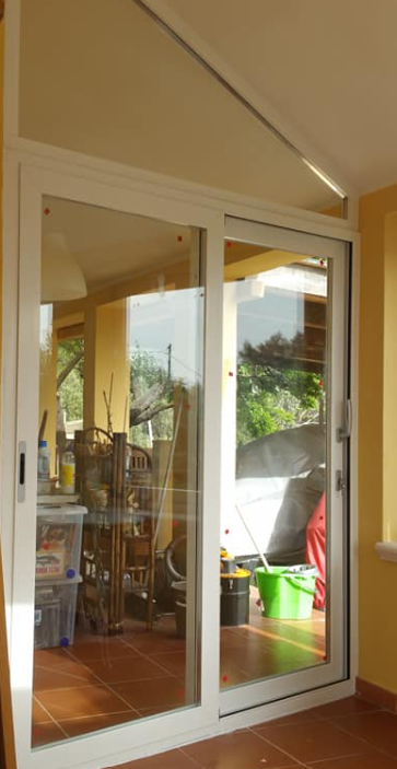 Le porte scorrevoli in vetro bianco si aprono su un portico, con vista su un'area esterna.