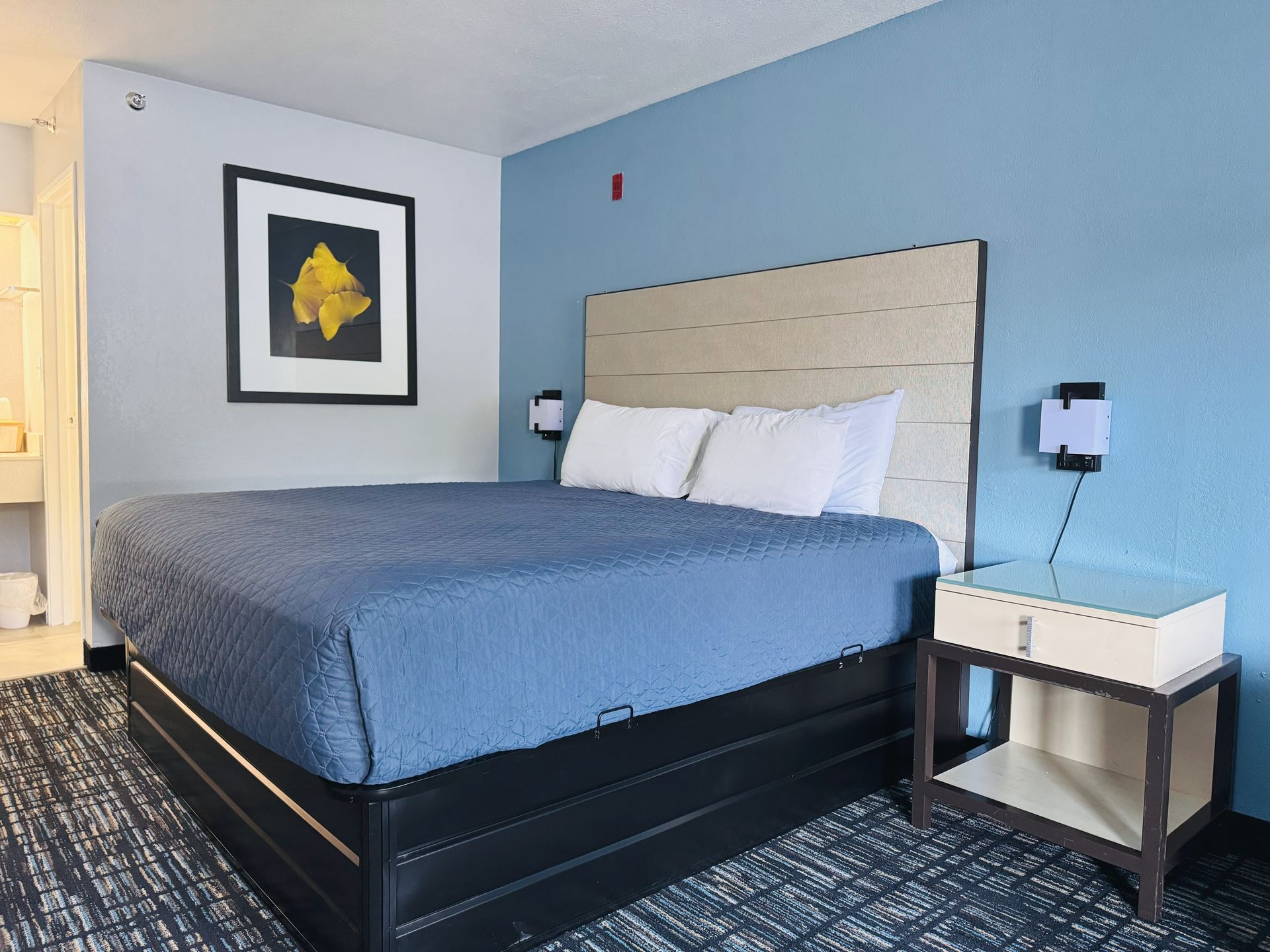 A hotel room with a king size bed and a nightstand