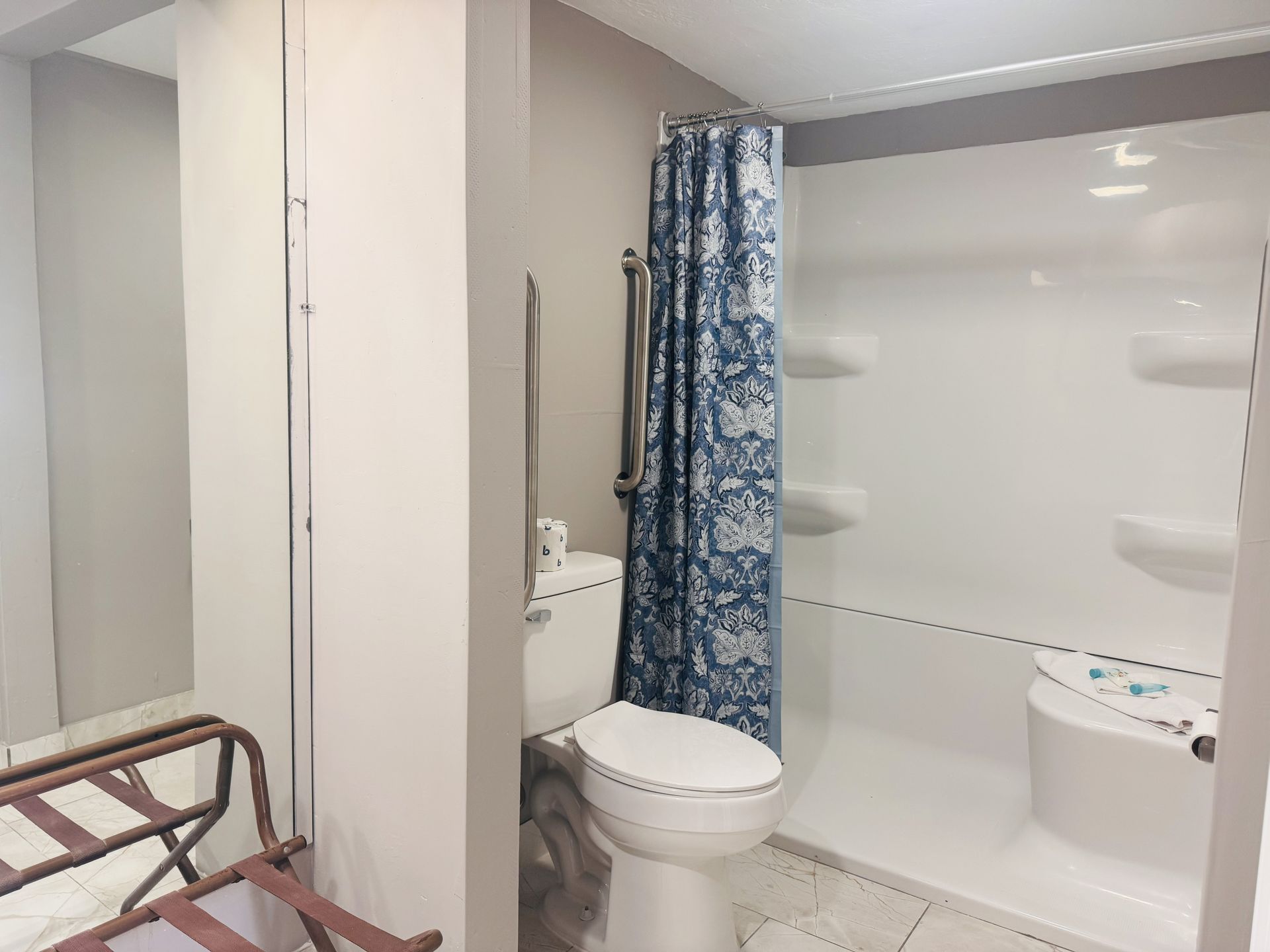 A bathroom with a toilet , shower and mirror.