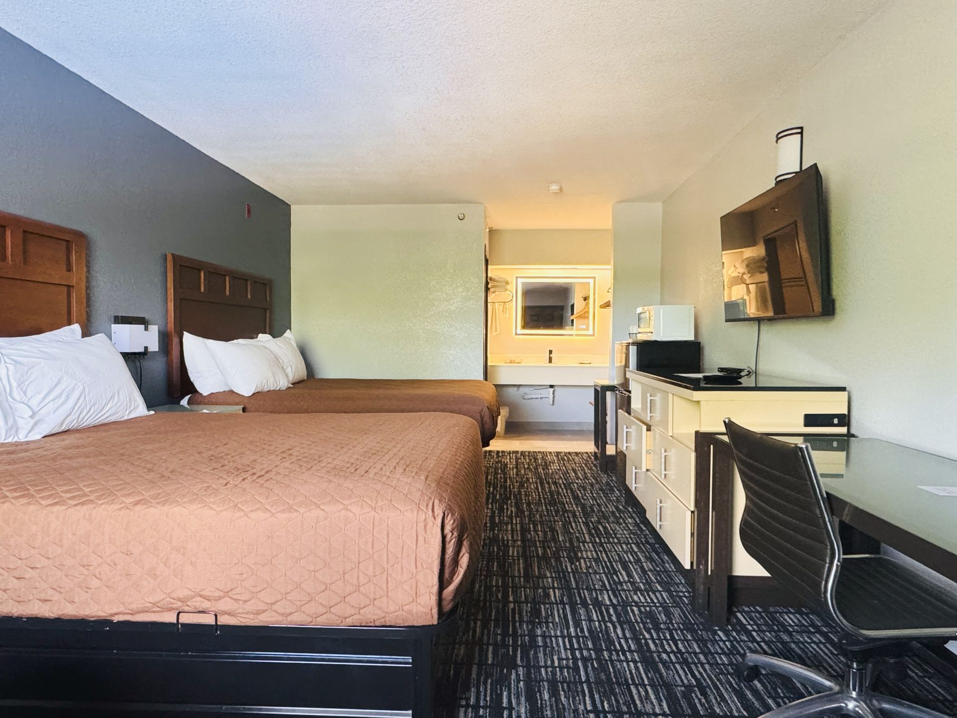 A hotel room with two beds , a desk and a television.