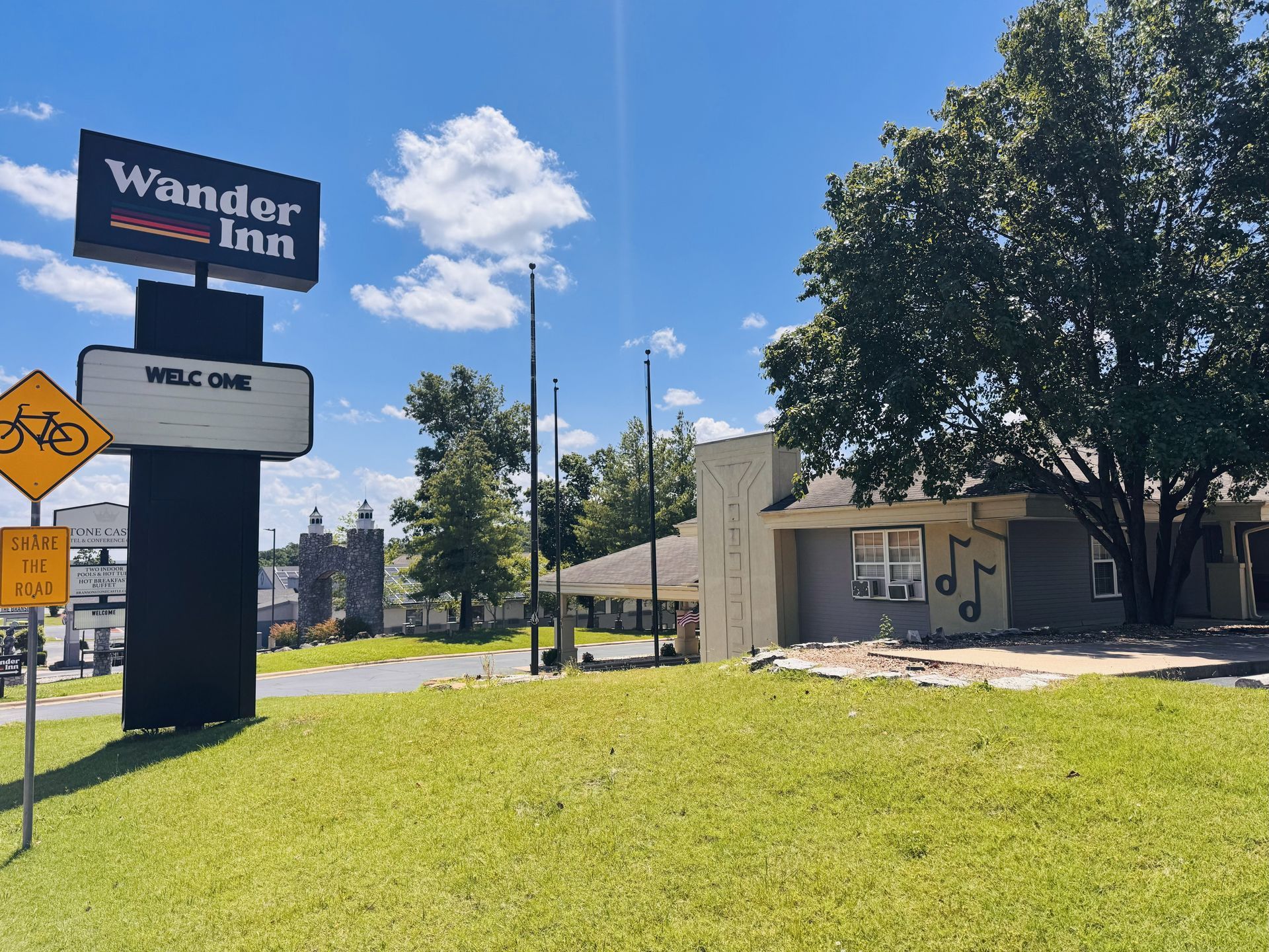A large sign for wander inn is sitting on top of a lush green field.