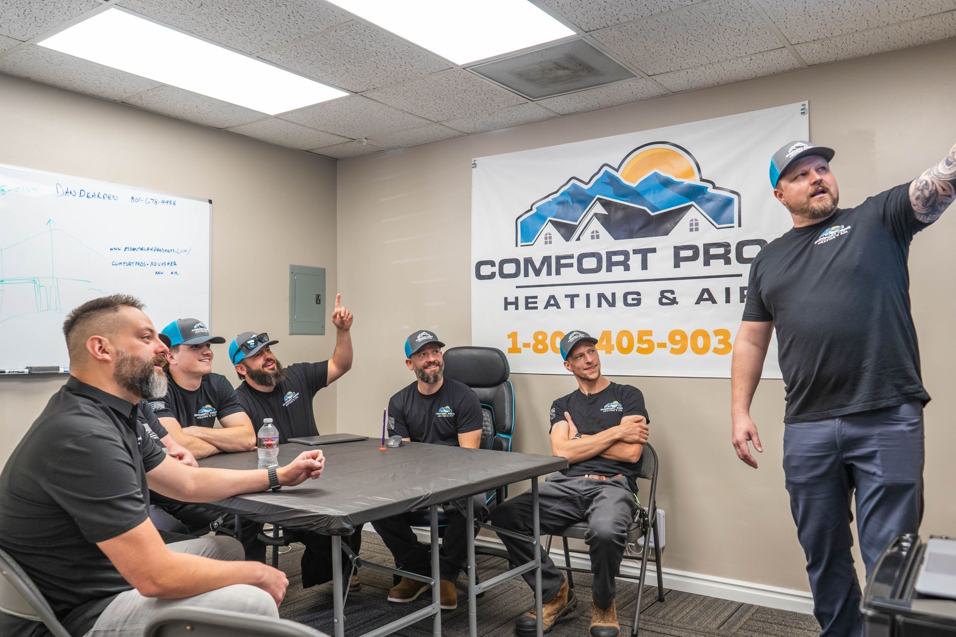 A man is talking to a couple of people while standing next to a trash can.