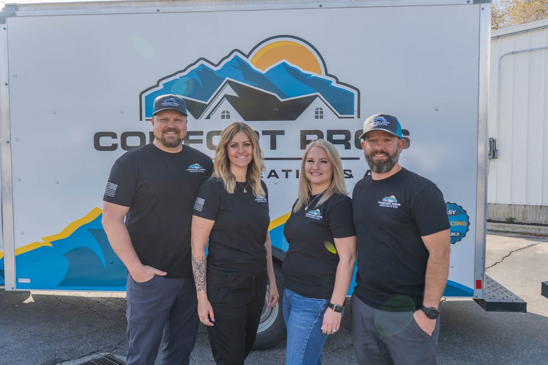 A woman is adjusting a thermostat on a wall while holding a cell phone.