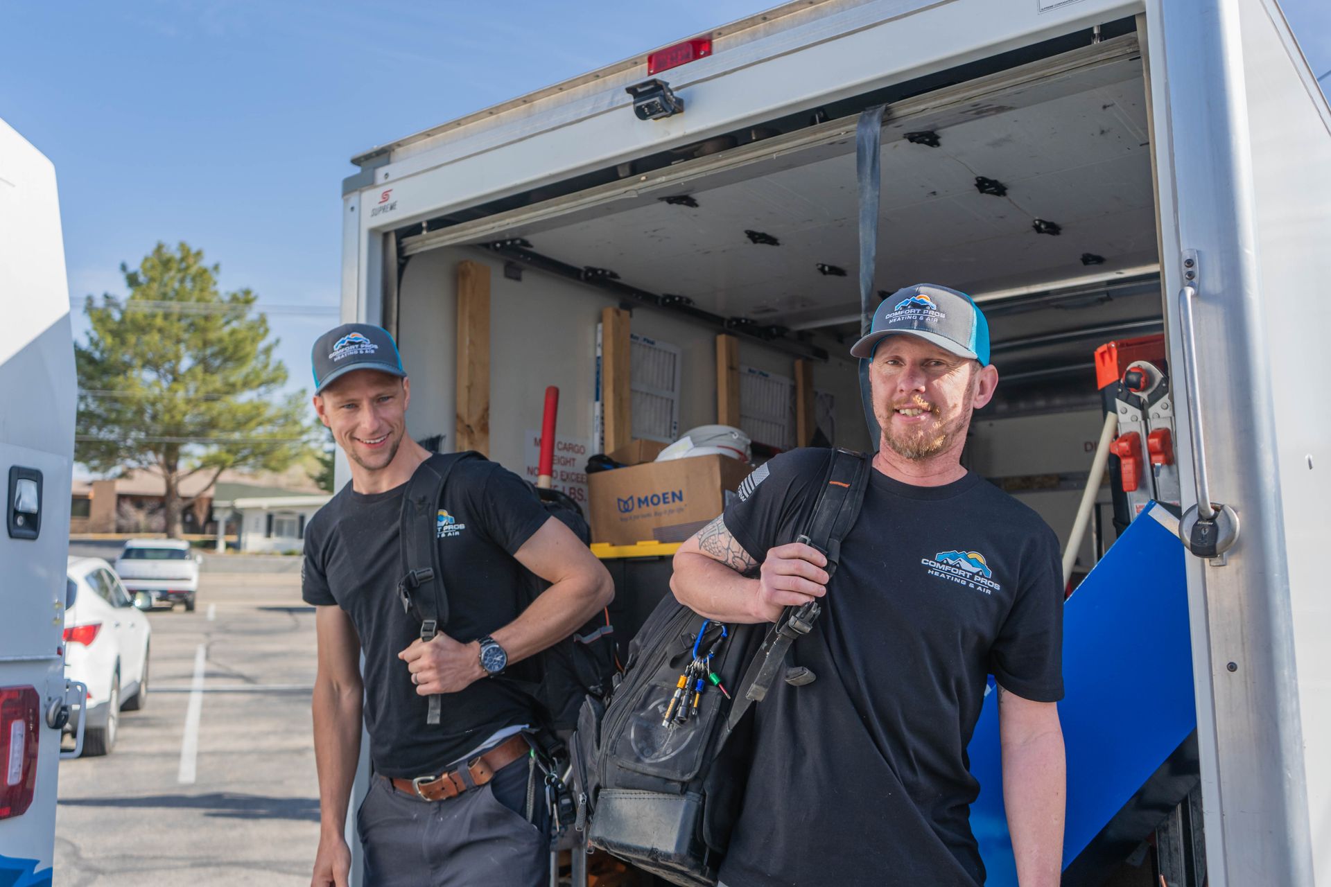 Two air conditioners are sitting next to each other on the side of a brick building.