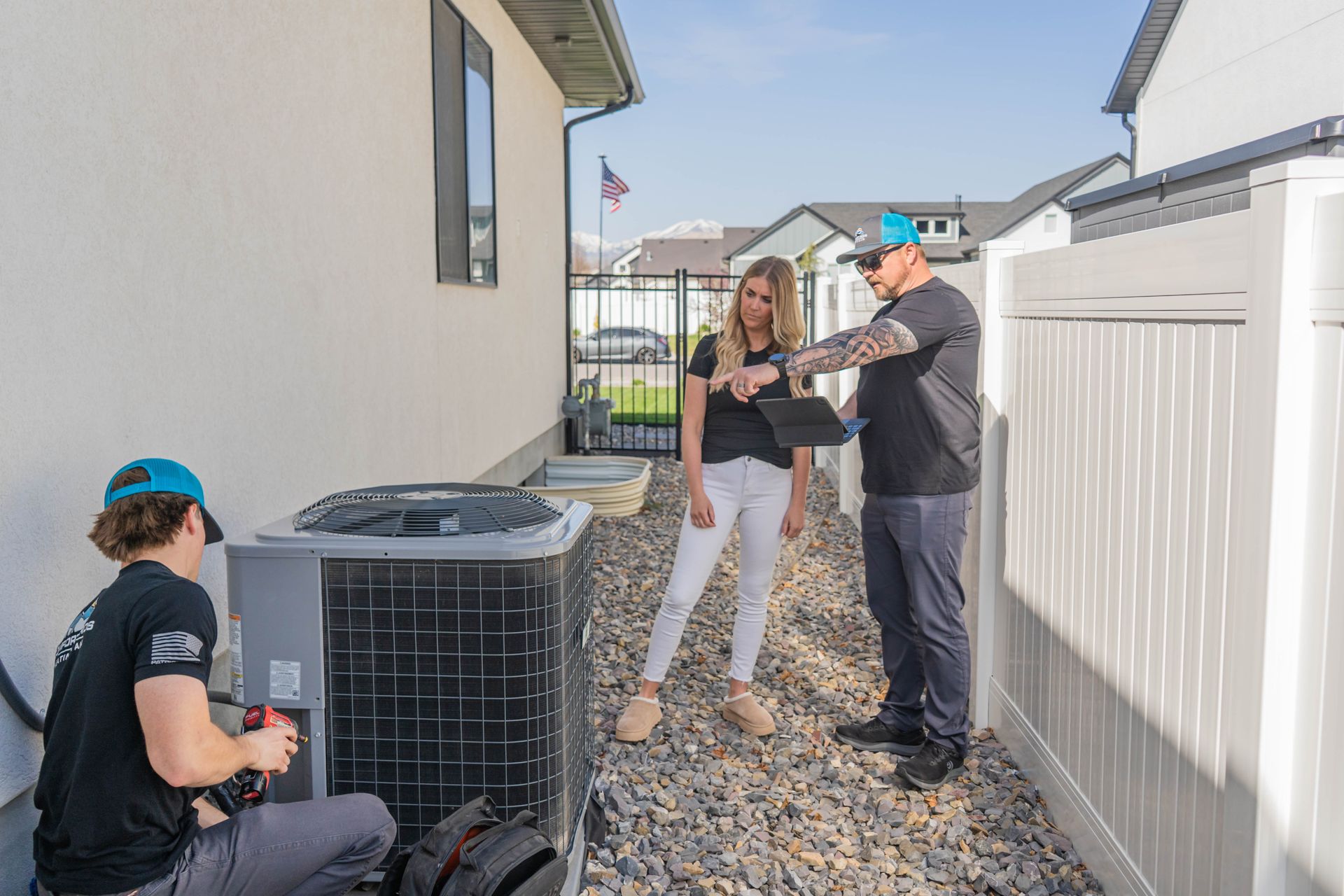 A man is working on an air conditioner while looking at a tablet.