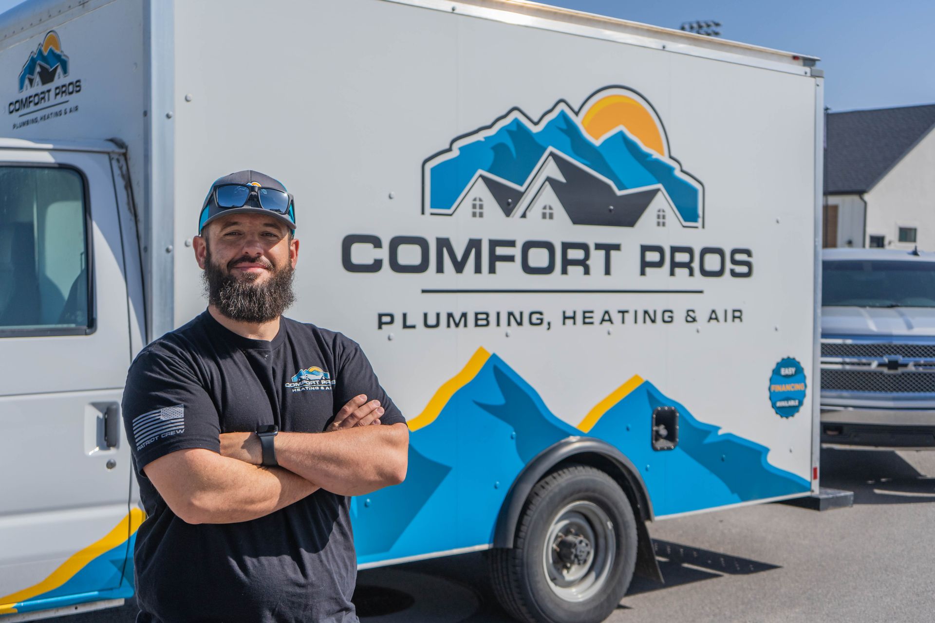 A woman is adjusting a thermostat on a wall while a man cooks in the background.