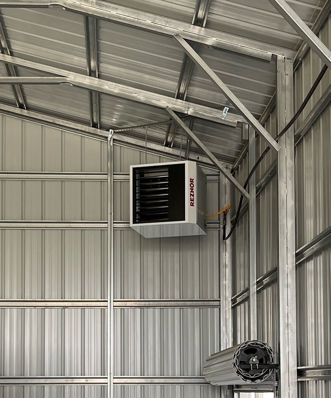 A large heater is hanging from the ceiling of a building.
