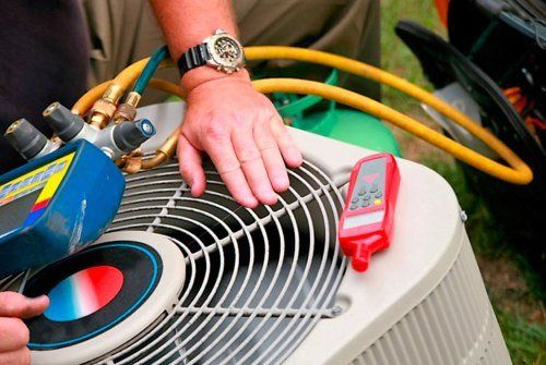 A man wearing a watch is working on an air conditioner.