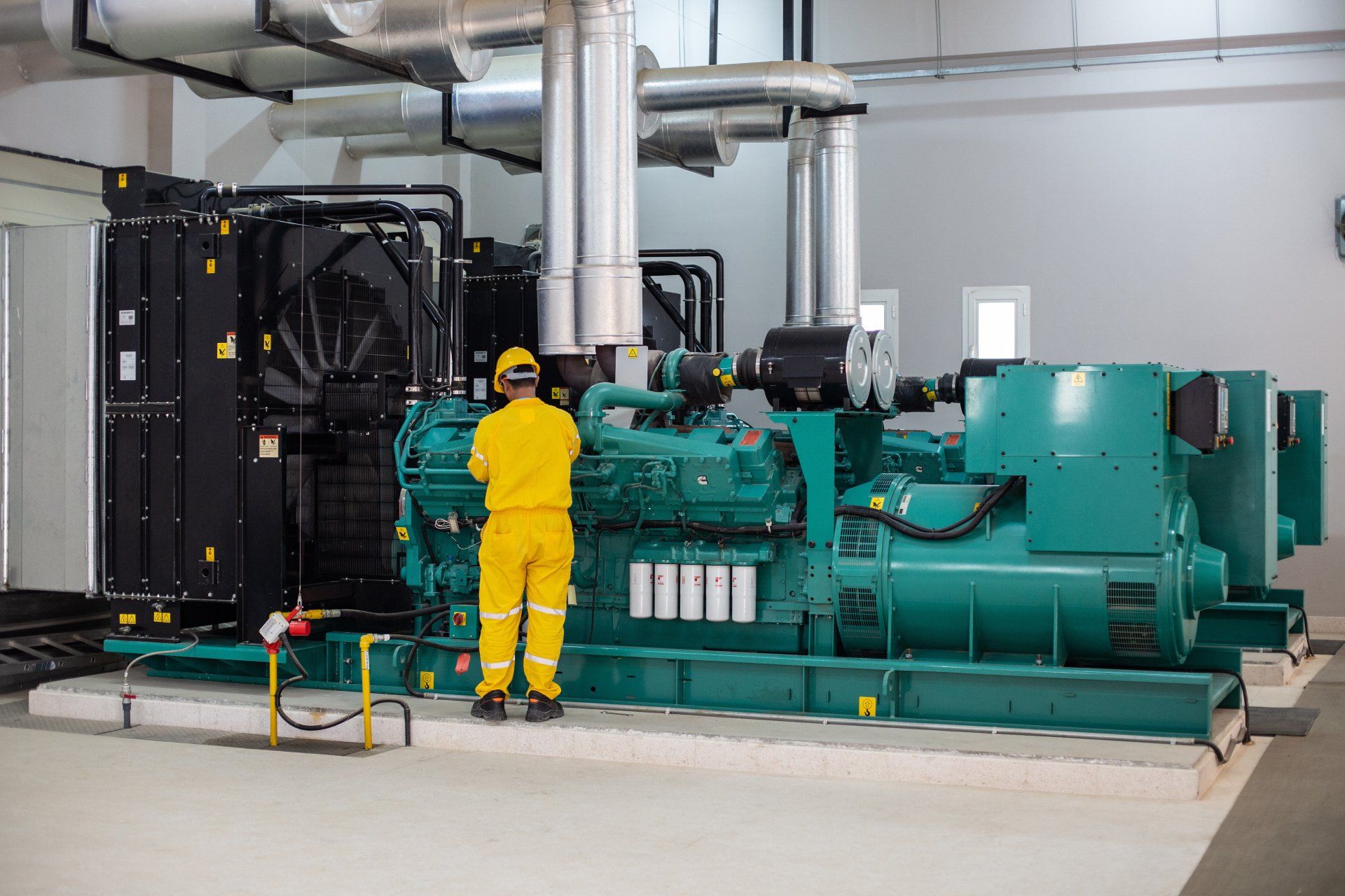 A man in a yellow suit is working on a generator in a factory.